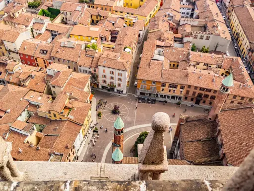 Vista aerea di Cremona: tetti rossi, piazze animate e torri. Un assaggio di cosa vedere a Cremona in un giorno.
