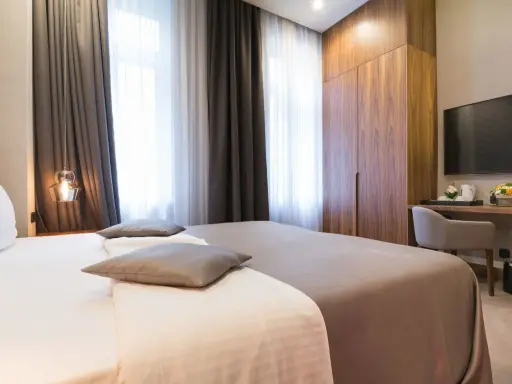 Eleganckie pokoje hotelowe: łóżko, szafa, biurko z TV. Idealne nazwy pokoi hotelowych dla komfortowego pobytu.