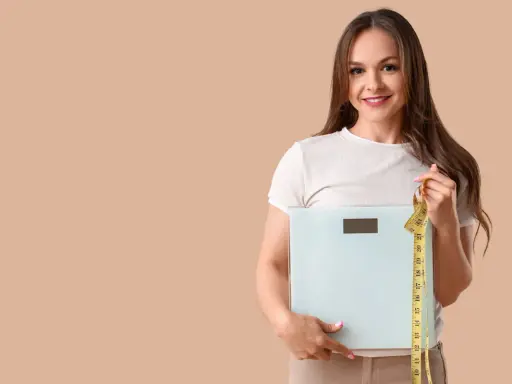 Femme souriante tenant une balance et un mètre ruban, prête à perdre 10 kilos.