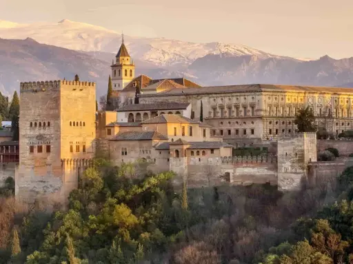 Die Alhambra in Granada, ein Traumziel nach einer Reise von Sevilla. Majestätische Festungsmauern und Paläste vor schneebedeckten Bergen.