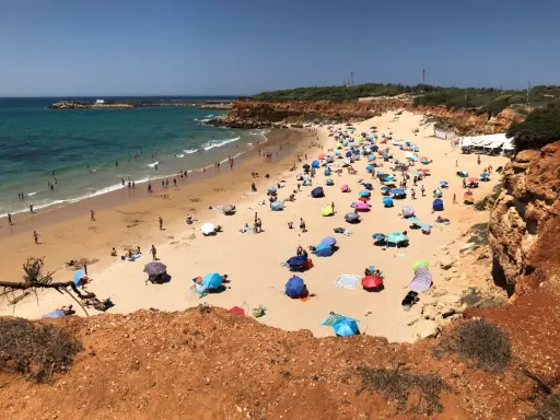 Sonniger Tag am playa fuente del gallo mit vielen bunten Sonnenschirmen und Badegästen im türkisfarbenen Meer.