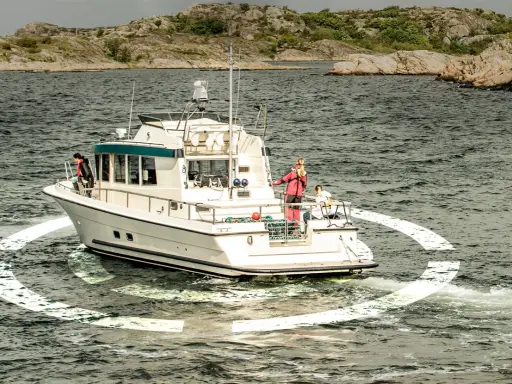 Un bateau navigue en mer, entouré d'une ancre virtuelle. Des personnes sont sur le pont, profitant de la croisière.
