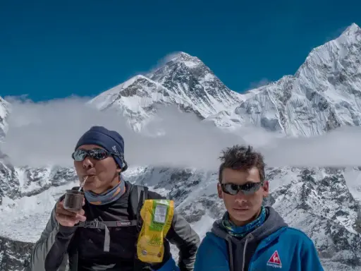 Niesamowity widok z Mount Everest. Dwóch wspinaczy odpoczywa, jeden pije yerba mate, podziwiając majestatyczne szczyty.