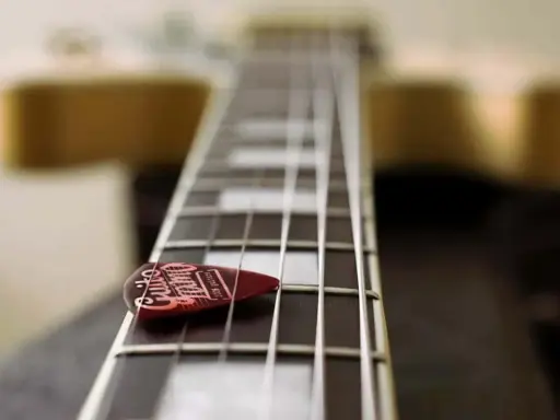 Médiator sur le manche d'une guitare, prêt à jouer une gamme arabe.