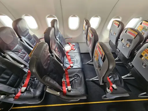 Puste fotele w samolocie Pegasus Airlines, gotowe na odprawę pasażerów. Czerwone pasy bezpieczeństwa czekają.