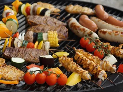 Una parrillada de que es bbq: brochetas de pollo y verduras, salchichas, bistecs y mazorcas de maíz asándose en una parrilla.