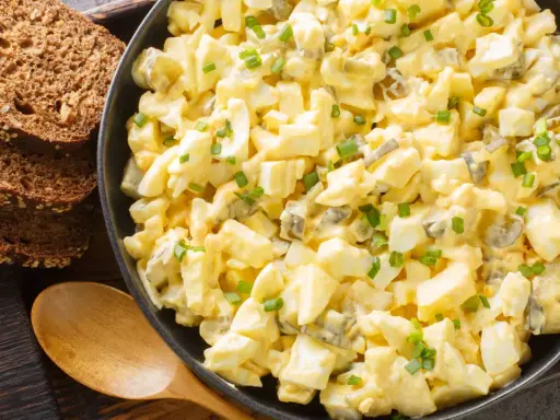 Cremiger Eiersalat mit Gurkenstückchen und Schnittlauch, garniert, serviert mit Vollkornbrot. Ein einfaches eiersalat rezept.
