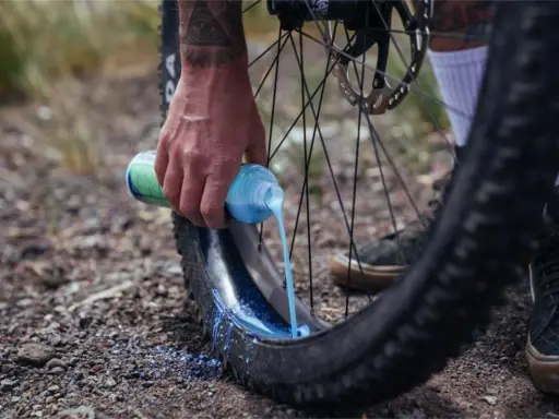 Ręka wylewa mleczko do opony rowerowej. To część przygotowania systemu **radial tubeless**, który zapewnia lepszą przyczepność i odporność na przebicia.