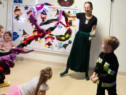 Wesołe zabawy integracyjne z czarownicami i magicznymi kluczami. Dzieci i nauczycielka bawią się w Halloweenowe gry.