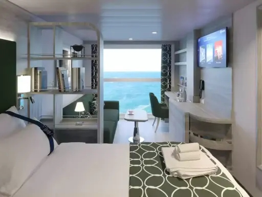 Interno cabina MSC World Europa: letto, divano, scrivania e vista mare.