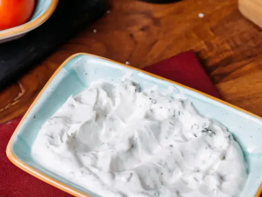 Sauce roquefort crémeuse et onctueuse, parsemée d'herbes vertes, dans un plat bleu clair. Parfait pour accompagner vos plats.