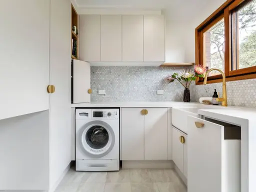 Lavanderia piccola moderna con lavatrice, lavello bianco, rubinetto dorato e finiture eleganti. Ottime idee per sfruttare ogni spazio.