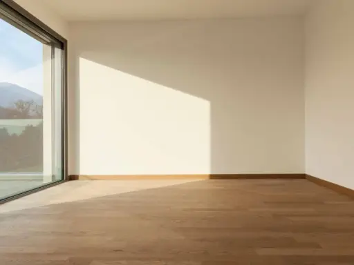 Habitación vacía con suelo de madera y gran ventanal de cristal planitherm que ofrece vistas a montañas.