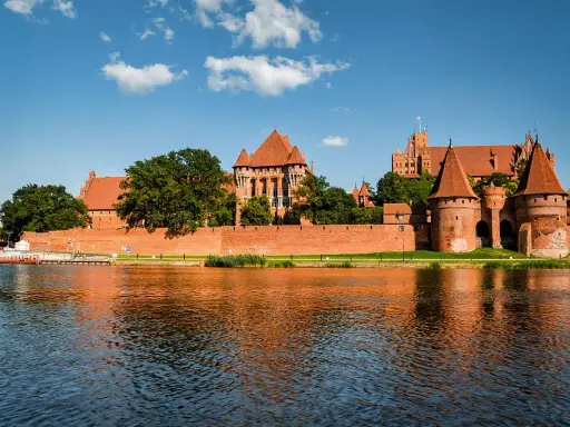 Potężny zamek w Malborku odbija się w wodzie. Zastanawiasz się, ile trwa zwiedzanie zamku w Malborku?