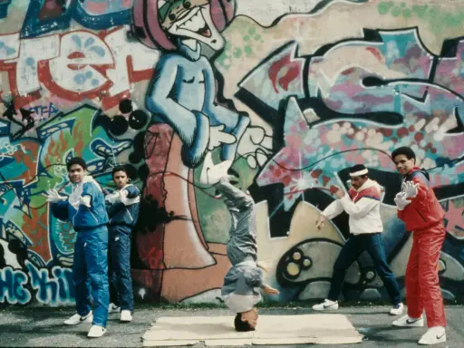A group of young people showcase their moves in front of vibrant graffiti art, embodying the spirit of hip hop culture art.