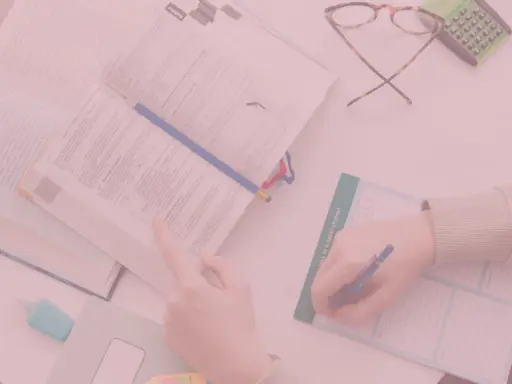 Uczniowie studiują, a na biurku leżą książki, okulary i kalkulator. Czy oceny na studiach mają znaczenie?