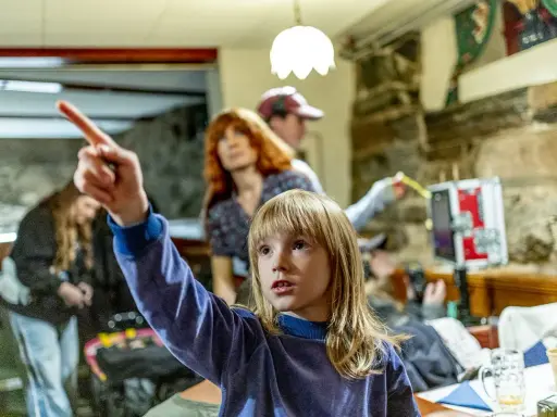 Barn pekar mot något spännande bakom filmerna. En kvinna med rött hår och en person med keps tittar också.