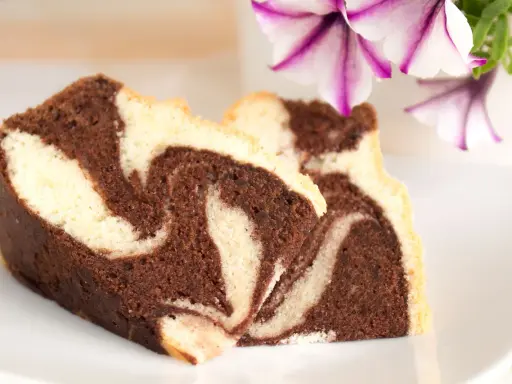 Zwei Stücke saftiger Marmorkuchen mit schöner Maserung, perfekt für ein gemütliches Kaffeetrinken. Dieses Marmorkuchen Rezept ist ein Klassiker.