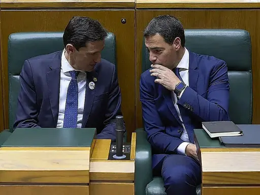 Dos hombres de traje azul conversan en un parlamento. Uno, con corbata de puntos, escucha atentamente. El otro, con la mano en la barbilla, parece reflexionar. ¿Qué debate se estará gestando?