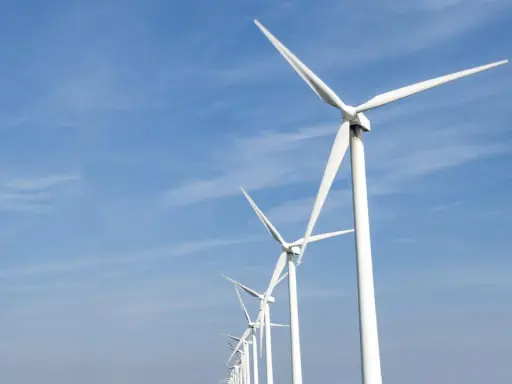 Reihe von Windrädern unter blauem Himmel, ein Symbol für Frankreichs Engagement für erneuerbare Energien.