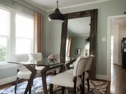 Un grand miroir rustique reflète la salle à manger, offrant une idée de où mettre un miroir dans une salle à manger pour agrandir l'espace.
