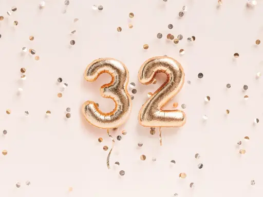 Złote balony z cyframi 3 i 2, otoczone konfetti. To już 32 tydzień ciąży, czas na świętowanie!