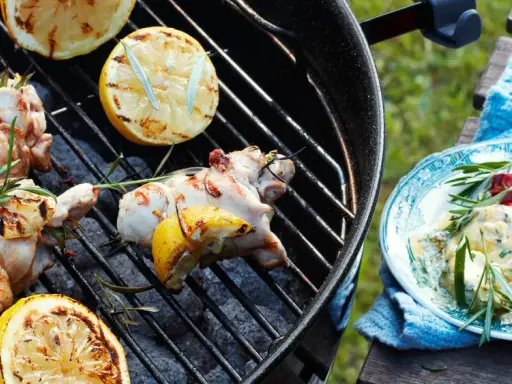Grillad kyckling med citron och rosmarin på grillen, redo att serveras med en krämig röra och chili.