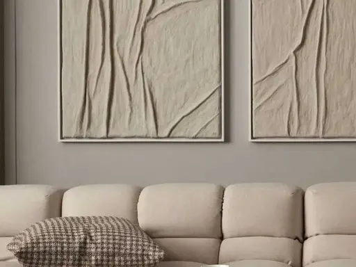 Deux tableaux texturés, style diy tableau relief, aux tons sable, accrochés au-dessus d'un canapé beige.