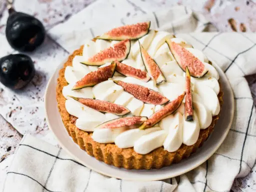Tarte aux figues fraîches et crème fouettée, décorée de feuilles d'or.