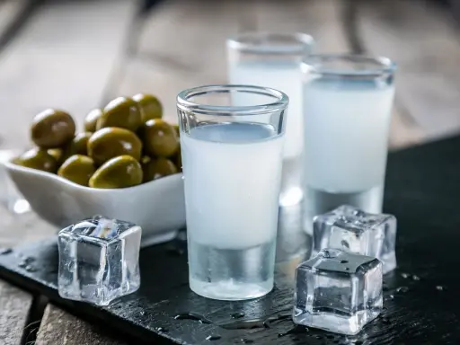 Trzy kieliszki z mlecznym ouzo, kostki lodu i miseczka oliwek. Tak pije się ouzo, by poczuć smak Grecji.