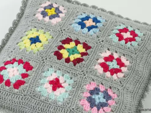 Szare szydełkowe poszewki na poduszki z kolorowymi wzorami w stylu granny square.