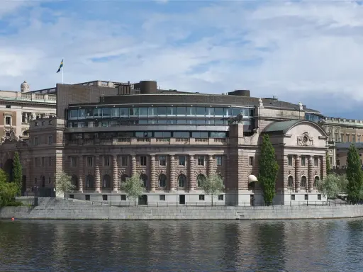 Riksdagshuset i Stockholm, en symbol för sveriges statsskick, med sin moderna glasdel och klassiska stenfasad vid vattnet.