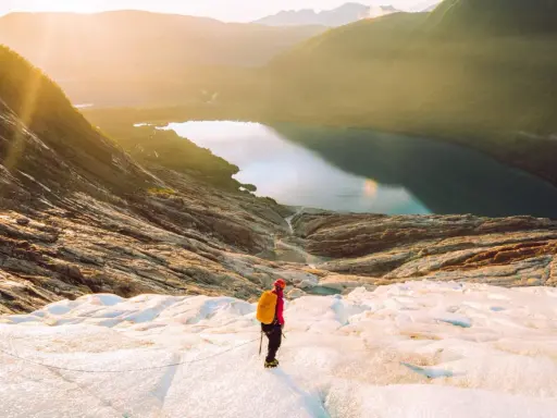 Vandrare på en glaciär i Norge med en sjö och berg i bakgrunden. En av många norge sevärdheter.