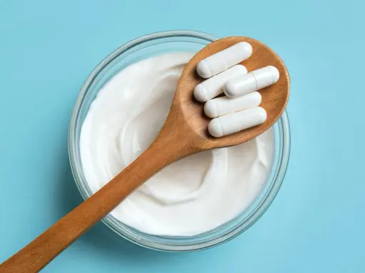 Cuillère en bois avec des gélules blanches sur un yaourt crémeux. Une question se pose : quel probiotique pour maigrir ?