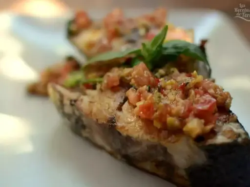 Deliciosa corvina a la plancha con un sofrito de tomate y hierbas frescas, servida en un plato blanco.