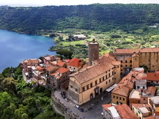 Nemi, un borgo incantevole a breve distanza da Roma, si affaccia sul lago. Case con tetti rossi si aggrappano alla collina, circondate da verde lussureggiante.