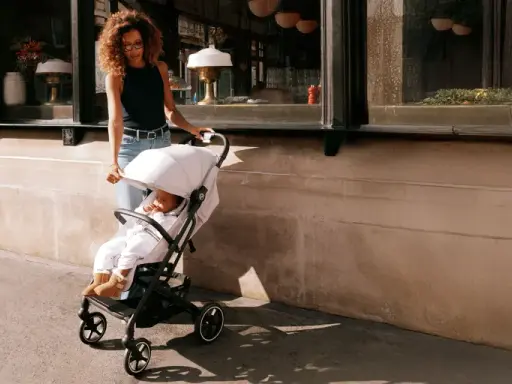 Kobieta prowadzi dziecko w wózku Cybex Beezy ulicą.