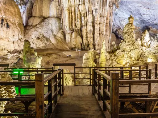 Drewniana kładka prowadzi przez imponujące jaskinie w Polsce, ukazując stalaktyty i stalagmity.