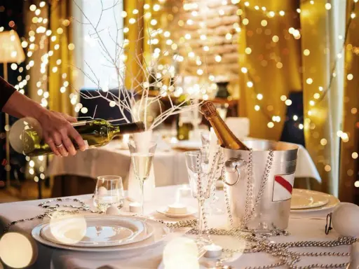 Mesa festiva con luces navideñas, champán y vino. Ideas para decorar un bar para Navidad con estilo y elegancia.