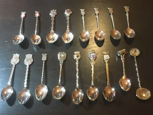 Collection de petites cuillères décoratives, chacune ornée d'un blason ou d'un symbole, révélant la valeur des petites cuillères de collection.