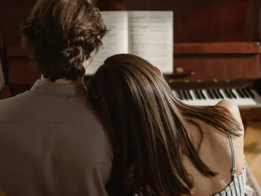 Pareja compartiendo un momento íntimo junto a un piano, el verdadero **exclusividad significado** de la conexión.
