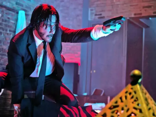 John Wick i svart kostym, med pistol i hand, redo för strid. Kanske en scen från John Wick 5.