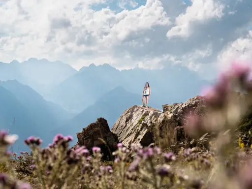 Una mujer en la cima de una montaña rocosa, disfrutando de las vistas. ¡Una gran idea de qué hacer en Cerler en verano!