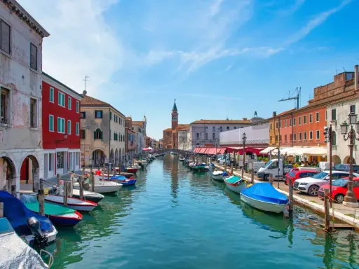 Vue d'un canal à Chioggia, Venise, avec des bateaux amarrés le long des maisons colorées.