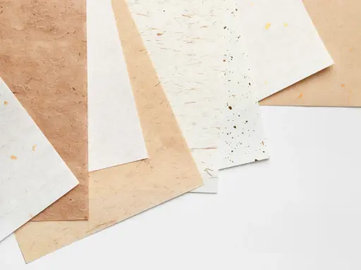 Różne rodzaje papieru, od jasnych po brązowe, z delikatnymi zdobieniami. Każdy papier to inna klasa papieru, idealna do twórczych projektów.