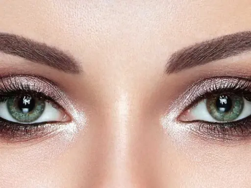 Ojos verdes deslumbrantes con un maquillaje ahumado y brillante, realzando su belleza natural.