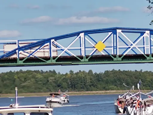 Żółty romb na niebiesko-białym moście to jeden z znaków kardynalnych na wodzie, wskazujący drogę wodną.