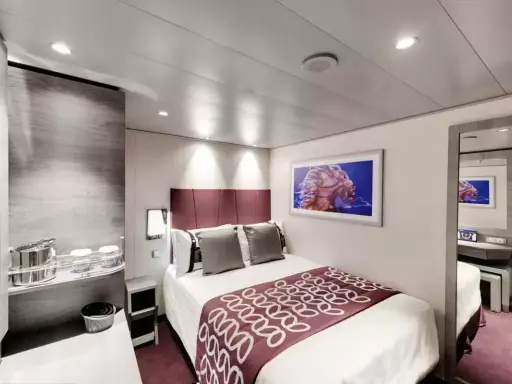 Cabina MSC Grandiosa ponte 8: letto matrimoniale, quadro con medusa, specchio e arredi moderni.