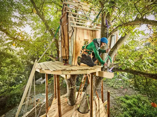 Mann baut Baumhaus für Kinder. Tolle baumhaus kinder ideen für Abenteuer im Grünen.