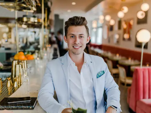 Uśmiechnięty menedżer firmy w jasnoniebieskiej marynarce siedzi przy barze w eleganckiej restauracji.